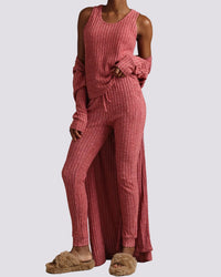 Person wearing a pink ribbed lounge set with slippers on a gray background