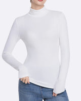 A woman wearing a fitted white long-sleeve mock neck turtleneck top with blue jeans, shown from the neck down against a light gray studio background.