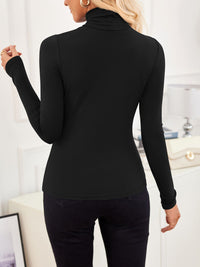 Back view of VRCÔMFY all-black ensemble with turtleneck top and tailored trousers, styled with beige gold-clasp bag and curated interior accents | Streamlined silhouette meets minimalist elegance in a sophisticated lifestyle setting