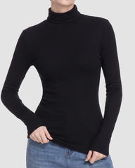 A woman wearing a fitted black long-sleeve turtleneck top with blue jeans, shown from the neck down against a light gray studio background.