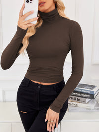 VRCÔMFY russet brown turtleneck cropped top with precision-tailored fit, paired with curated distressed black jeans against a literary backdrop | Urban scholarly aesthetic meets architectural minimalism for intellectually-inspired street style