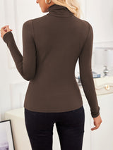 Back view of VRCÔMFY mocha brown turtleneck top with sculpted silhouette, styled with tailored black trousers and sand beige bag featuring gilded lock-clasp | Architectural minimalism and refined urban elegance in a curated lifestyle setting