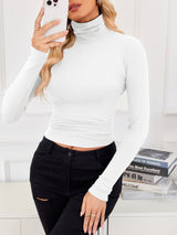 VRCÔMFY porcelain white cropped turtleneck top with architectural lines, paired with artfully ripped black jeans | Urban minimalist edge and sculpted sophistication for versatile street-style elegance