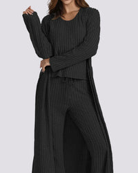 Woman wearing a black ribbed sweater and pants set on a gray background