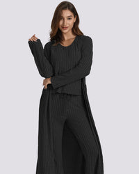 Woman wearing a black ribbed outfit with a long duster on a gray background