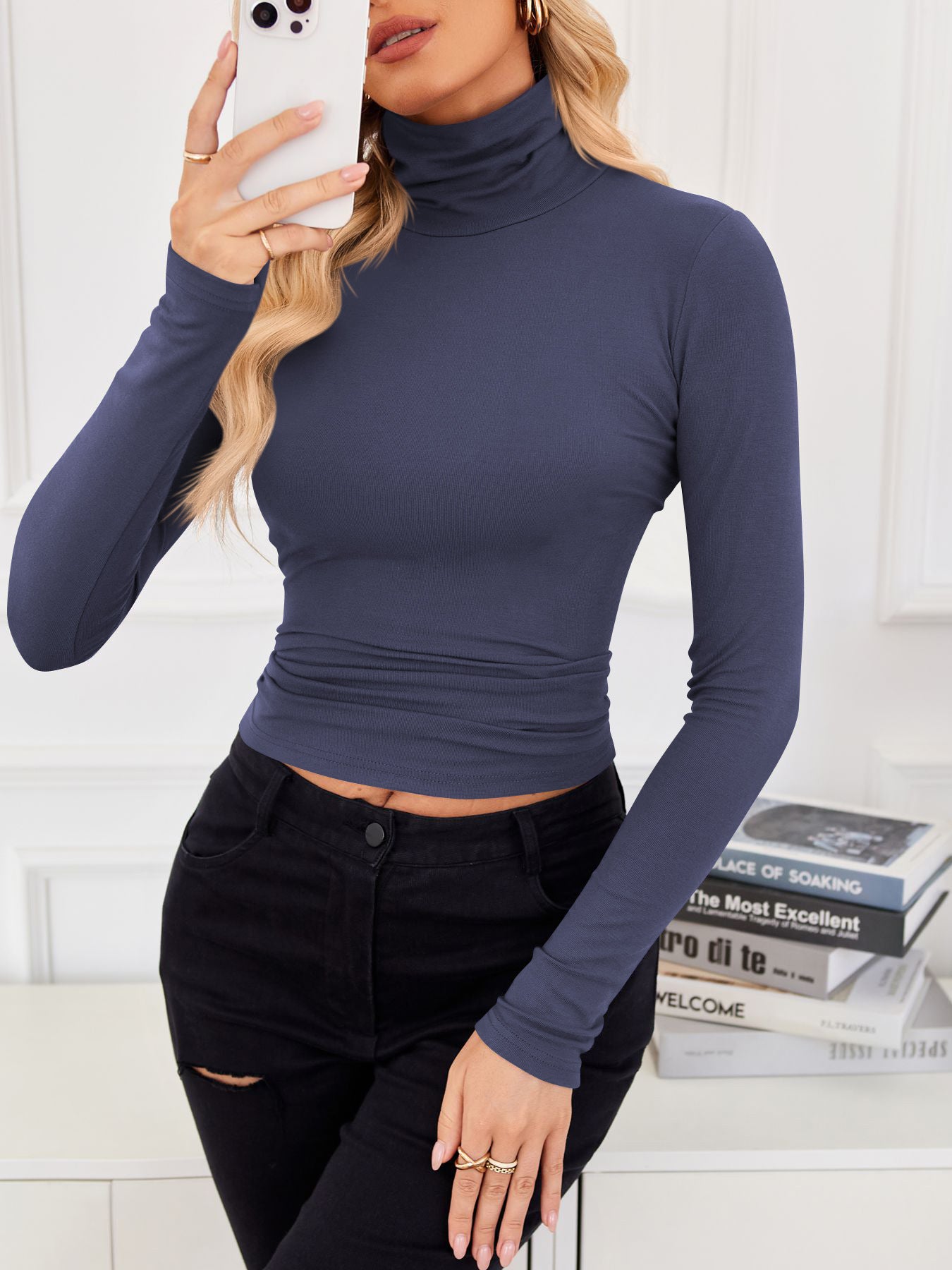 VRCÔMFY twilight blue cropped turtleneck top with contour-defining fit, styled with artfully distressed black jeans against a curated literary backdrop | Urban intellectual edge and architectural minimalism for the modern cosmopolitan woman