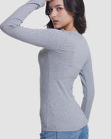 A woman wearing a fitted light gray long-sleeve top, shown from the back and side against a plain light gray studio background.