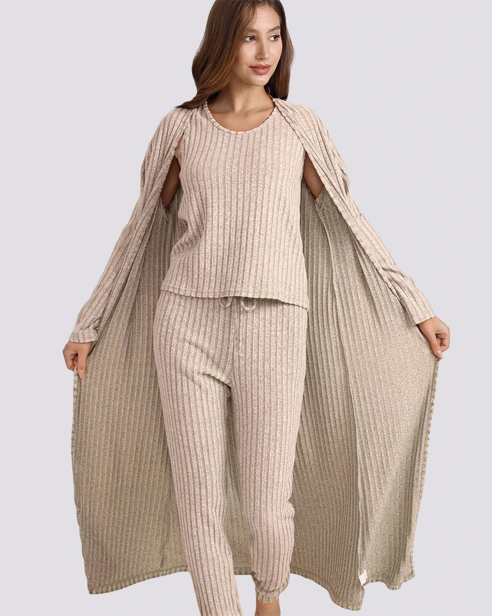 Woman wearing a beige ribbed outfit with a matching long cardigan on a gray background
