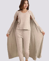 Woman wearing a beige ribbed outfit with a matching long cardigan on a gray background