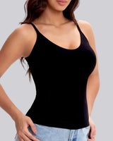 A woman wearing a black scoop-neck spaghetti-strap tank top paired with light-wash blue jeans, shown against a solid gray studio background.