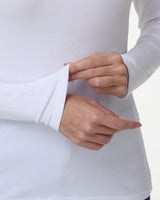 Close-up of a person wearing a white ribbed long-sleeve top, adjusting the cuff with both hands against a clean white background.