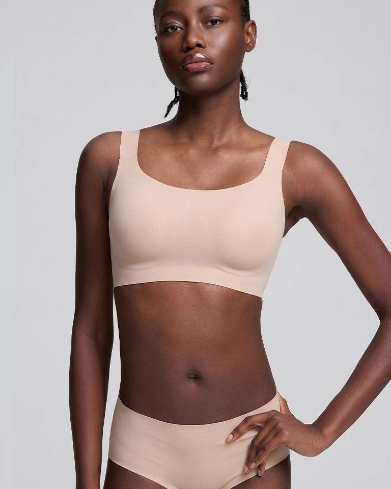 A model wearing a light beige seamless bralette and matching high-waisted briefs against a solid light gray background.