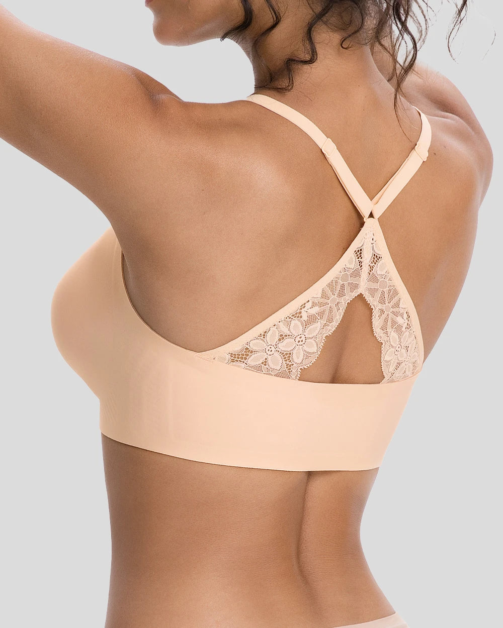 Rear view of a woman wearing a nude beige wireless bra with delicate lace back straps and a crisscross design, highlighting the comfortable seamless fit and elegant back detail.