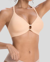 Close-up of a woman wearing a peach beige wireless bra with a center cutout and metallic ring detail, featuring a smooth seamless design for comfortable everyday support.