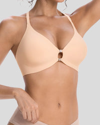 Close-up of a woman wearing a peach beige wireless bra with a center cutout and metallic ring detail, featuring a smooth seamless design for comfortable everyday support.