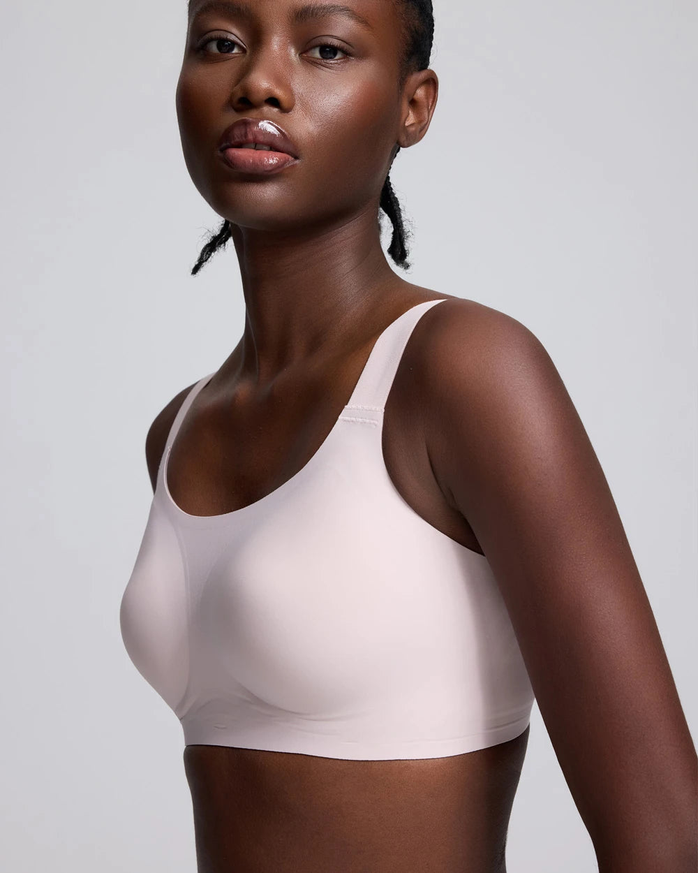 VRCÔMFY light beige wireless bralette with seamless support and a minimalist design, side view of a model against a light gray studio background.