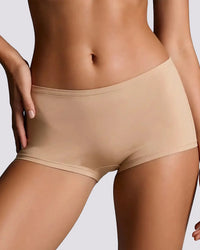 Close-up of a model wearing high-waisted, seamless shapewear briefs in a light beige shade against a neutral gray background.
