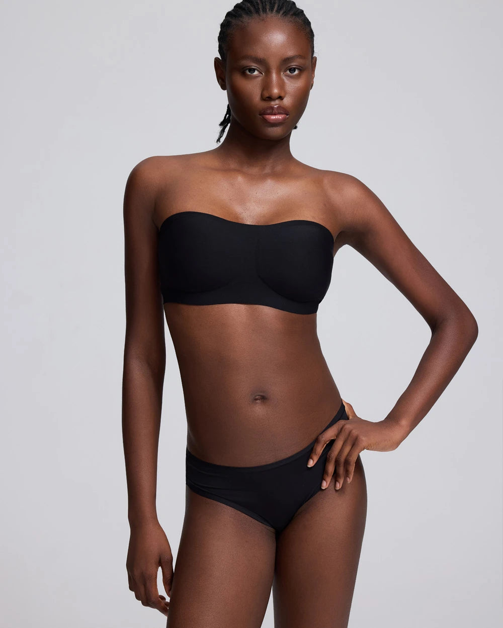 VRCÔMFY black strapless wireless bandeau bra with seamless support and a minimalist design, modeled against a light gray studio background.