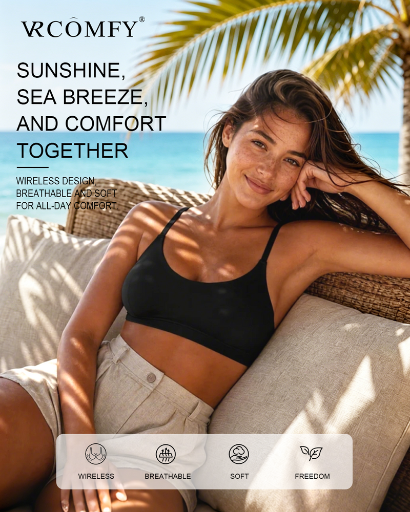 Woman in black wireless bra and beige shorts sitting on a beach chair with palm trees and ocean in the background.