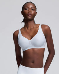 A woman modeling a blue wireless bra against a light gray studio background.