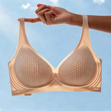 Lightweight beige breathable bra with perforated cups, held up against a clear blue sky to highlight comfort and airflow.