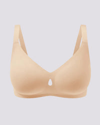 A light beige wireless bra with a small teardrop-shaped cutout at the center of the bust, displayed against a solid light gray background.