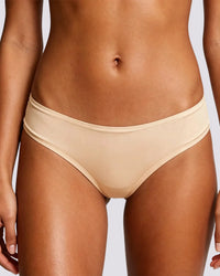 Beige ribbed bikini bottom worn by a model, shown from the waist to upper thighs against a light gray studio background.