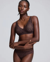 Woman wearing a leopard print seamless wireless bralette and matching high-waisted briefs, featuring soft fabric, comfortable support, and a stylish everyday design.
