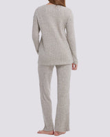 A woman shown from the back wearing a ribbed knit two-piece pajama set in a light oatmeal beige color, consisting of a long-sleeve top and matching pants, against a solid light gray background.