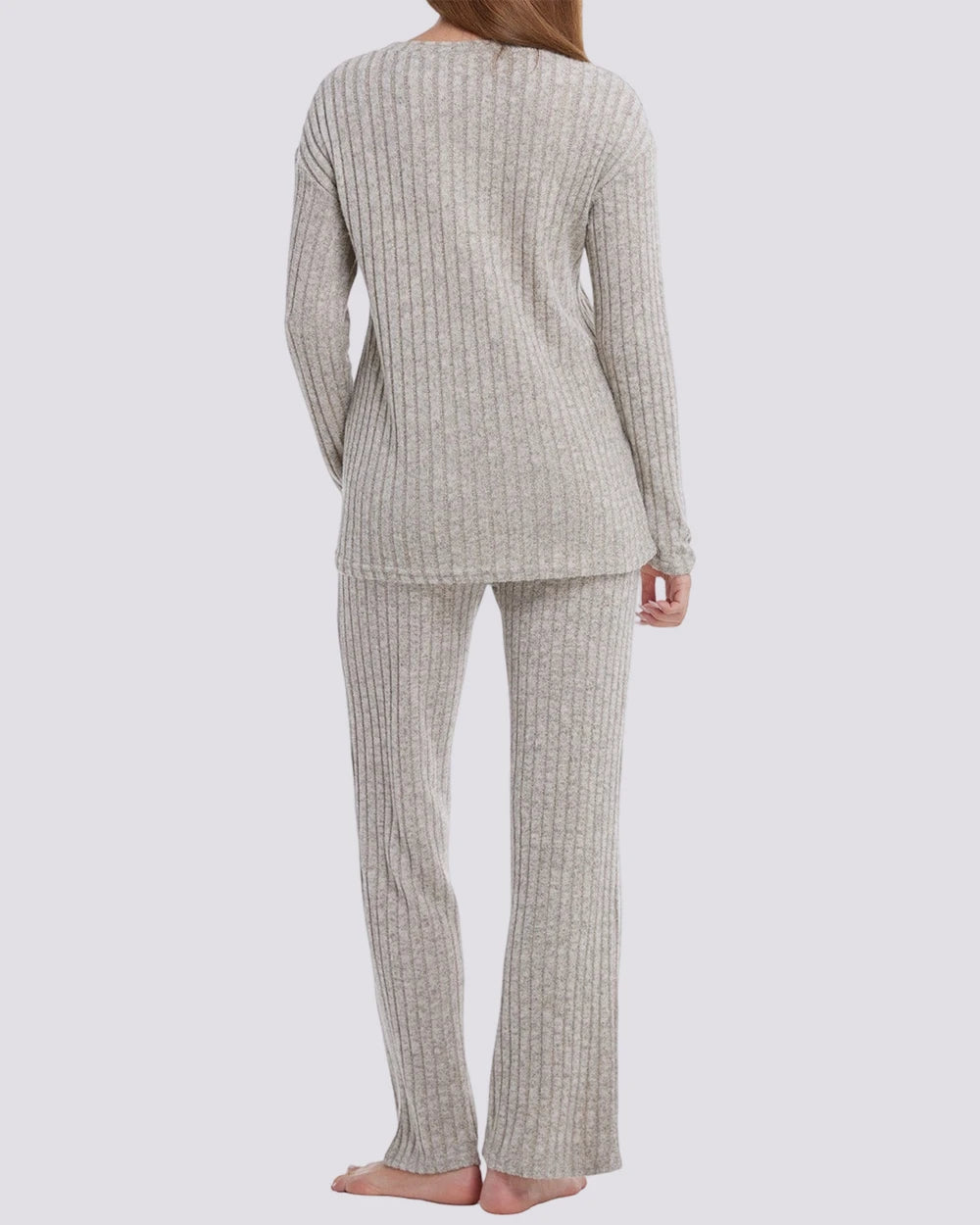 A woman shown from the back wearing a ribbed knit two-piece pajama set in a light oatmeal beige color, consisting of a long-sleeve top and matching pants, against a solid light gray background.