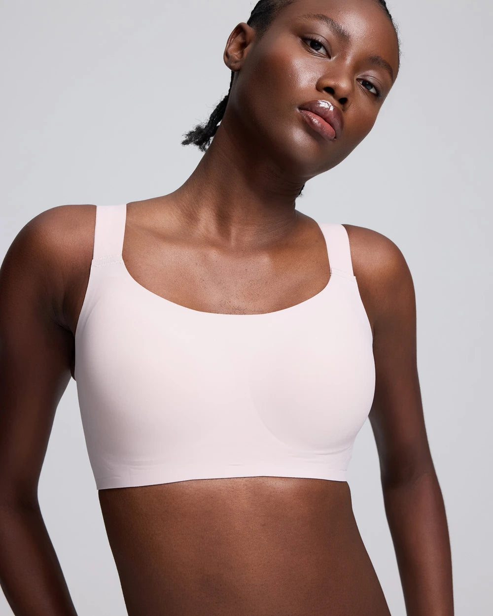VRCÔMFY light pink seamless bralette with soft stretch fabric and wireless support, close-up front view of a model against a light gray studio background.