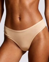 Close-up of a model wearing a beige bikini bottom against a light gray background.