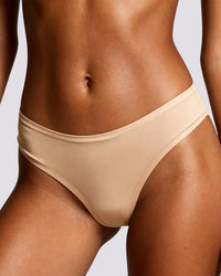 Close-up of a model wearing a beige bikini bottom against a light gray background.