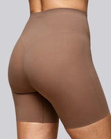 Close-up of a model wearing high-waisted seamless shapewear shorts in a solid taupe-brown color, shown from a rear three-quarter angle against a solid gray background.