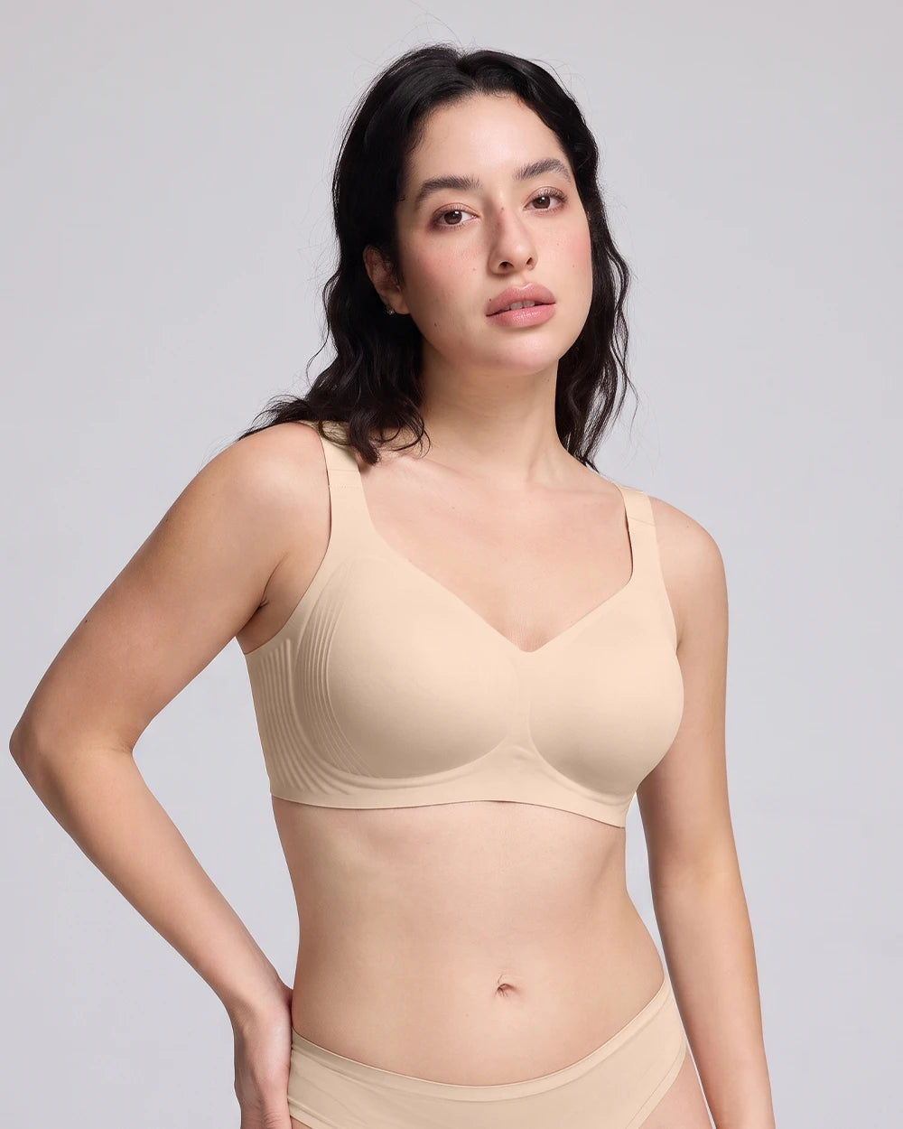 Woman wearing a nude seamless wireless scoop neck bra with soft fabric, smooth support, and a comfortable everyday fit.