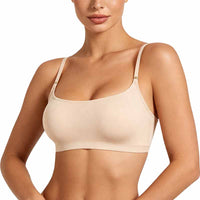 A woman wearing a beige wireless bra with thin adjustable shoulder straps and small gold-tone metal accents at the strap joints, shown against a plain white studio background.