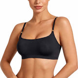 A woman wearing a black bralette with thin straps and small gold-tone hardware at the strap attachments, shown against a plain white studio background.