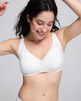 A woman wearing a vrcomfy white seamless underwire bra, shown from the chest up against a light gray studio background.