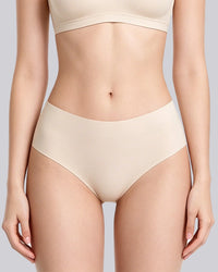 A model wearing high-waisted, seamless underwear in a light beige shade, paired with a matching bra top, shown against a solid light gray background.