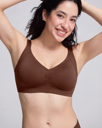 A woman wearing a brown V-neck bralette with a gathered center front, shown against a light gray studio background.
