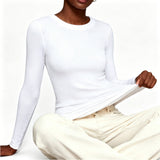 Person wearing a white long-sleeve top and beige pants on a white background