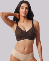 A woman modeling a leopard-print underwire bra and beige high-waisted briefs against a solid light gray background.