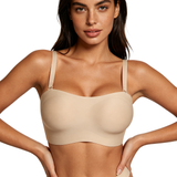 Woman wearing a beige bralette against a plain background
